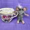 Mouse sits beside pretty little cup